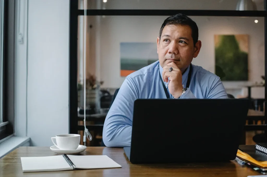person thinking while sitting behind a laptop